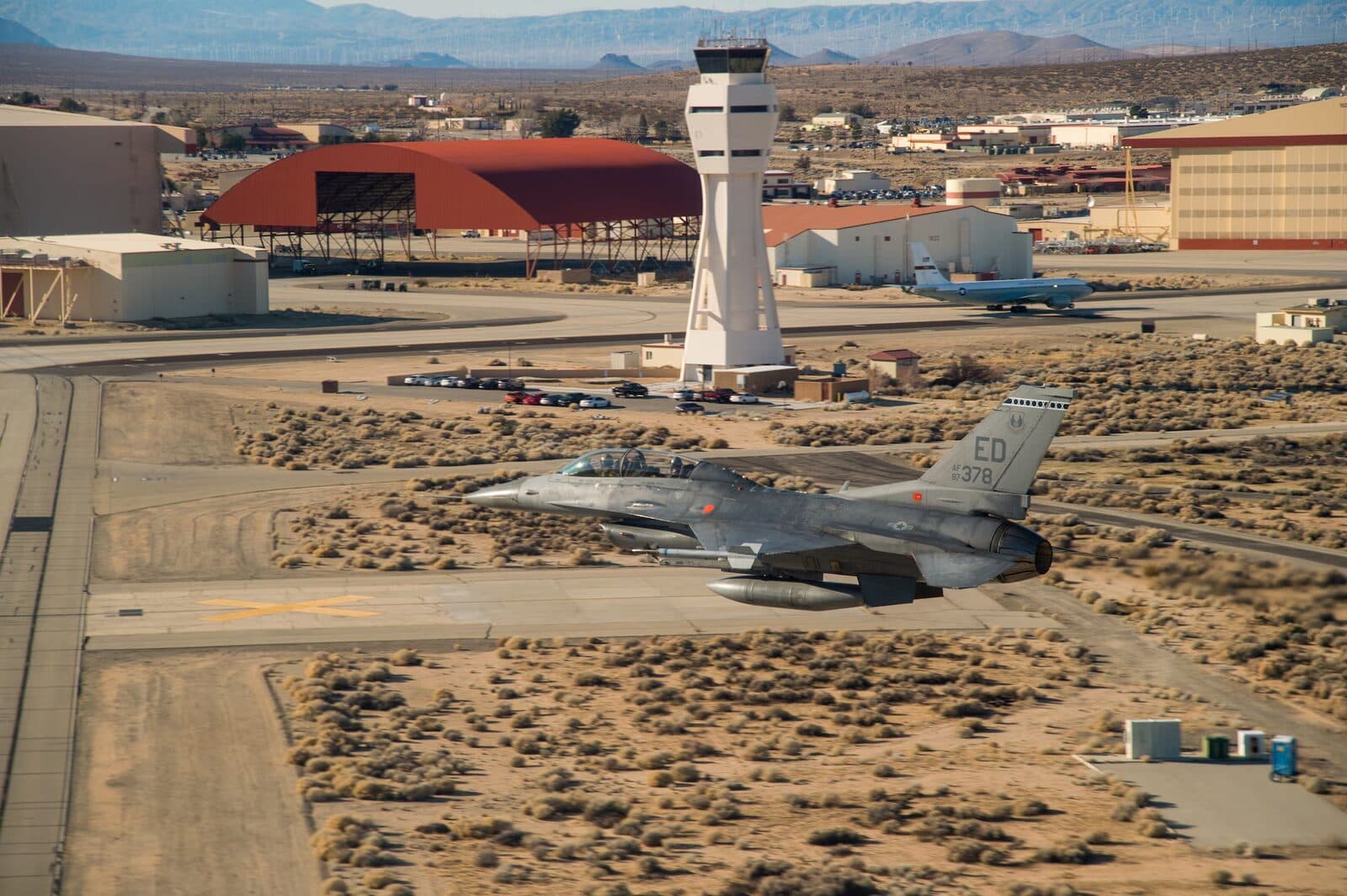 F-16 fighter jet over a military airbase with control tower